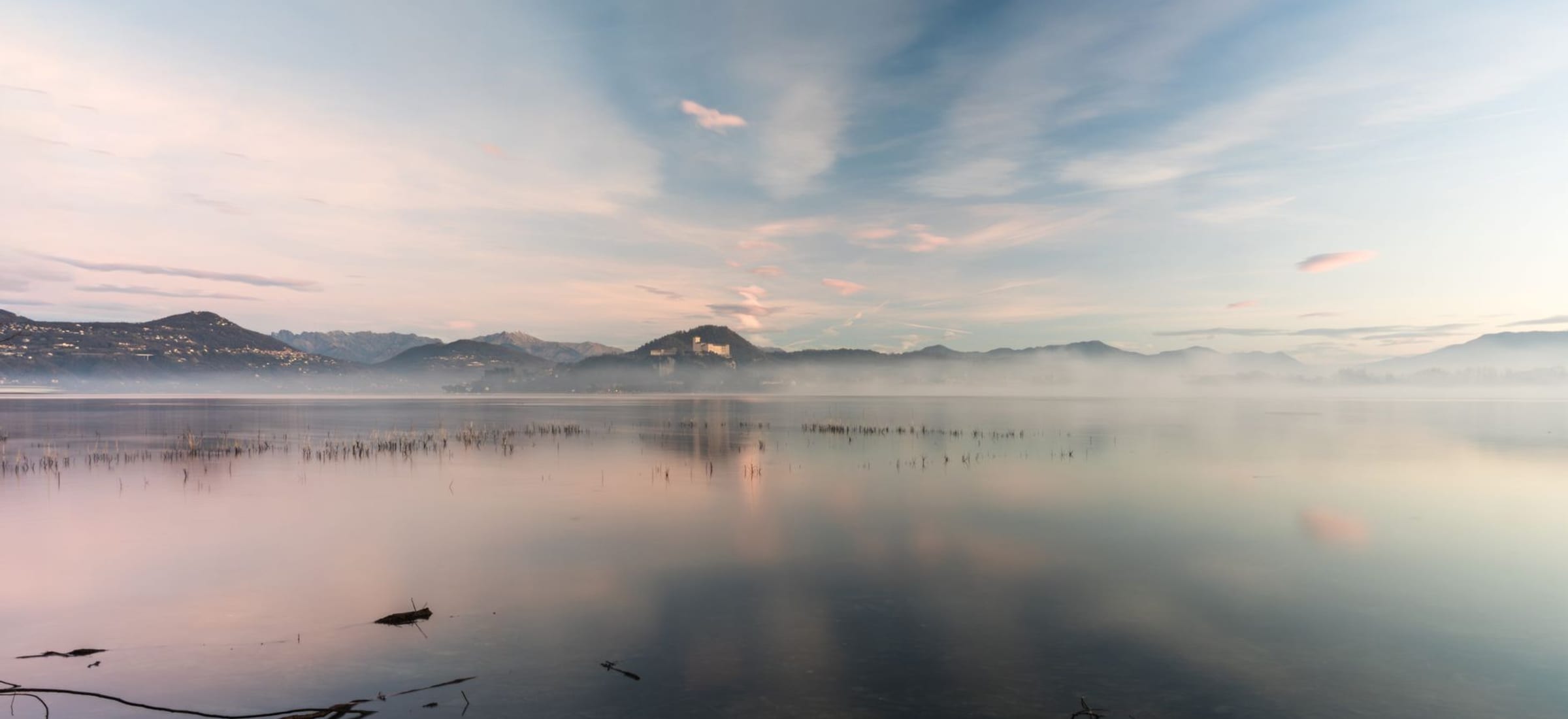 A calm lake at dawn under soft warm light